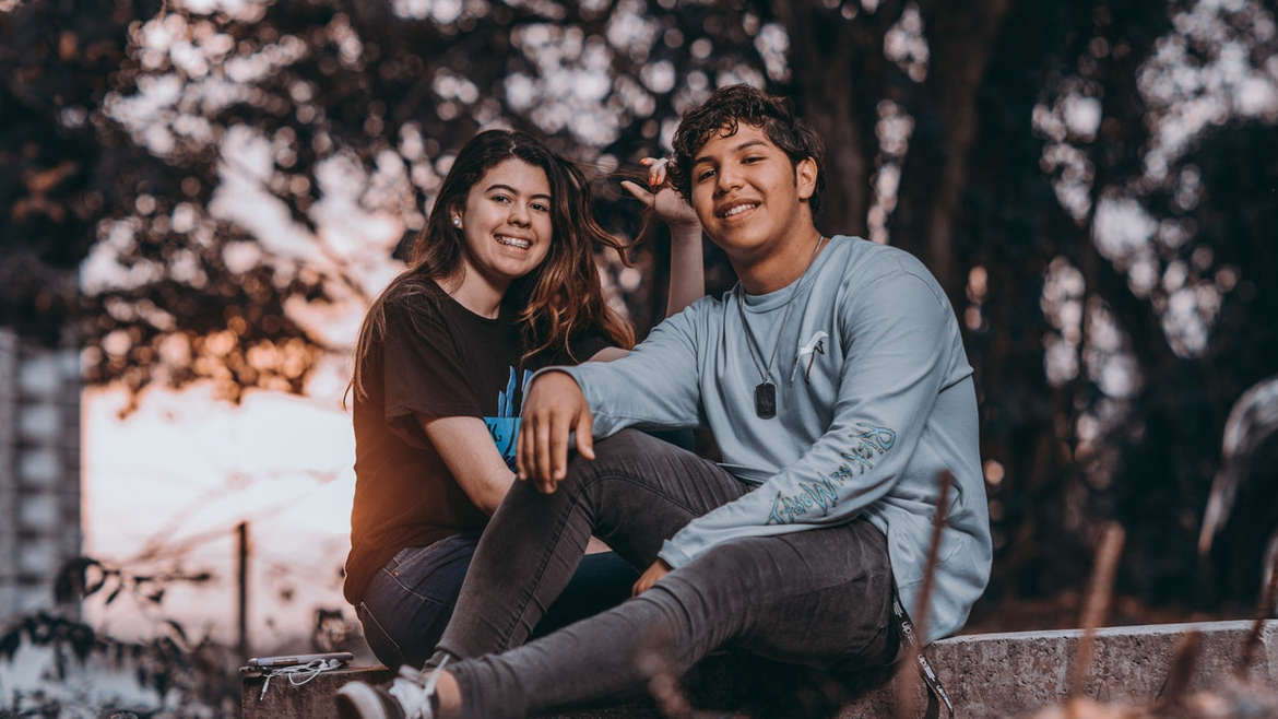 Teenage boy and girl sitting together, smiling